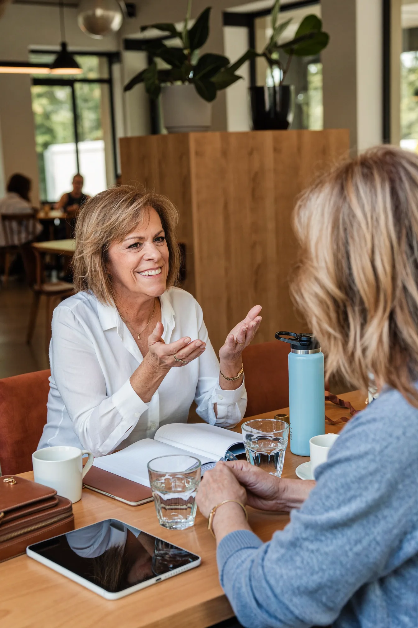 Jill Prescott smiling and talking warmly with a client over coffee at a cafe table